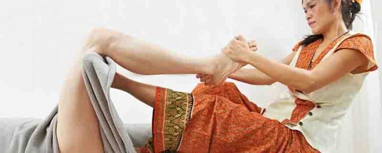 A person wearing a traditional outfit performs a massage on another persons foot